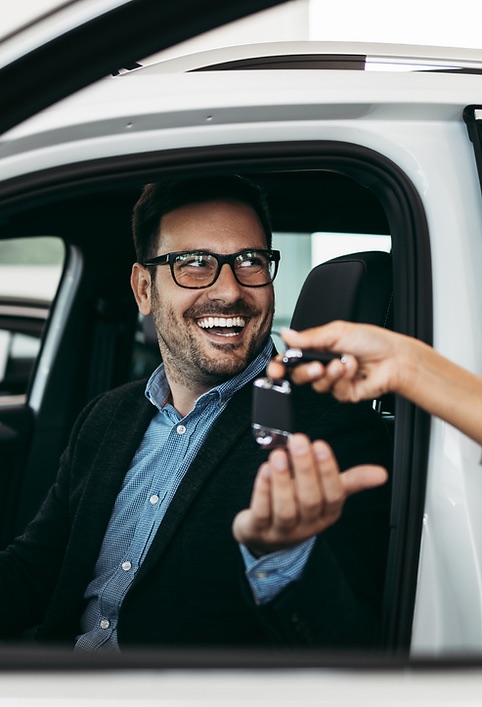 Cliente sonriente recibiendo las llaves de su auto nuevo