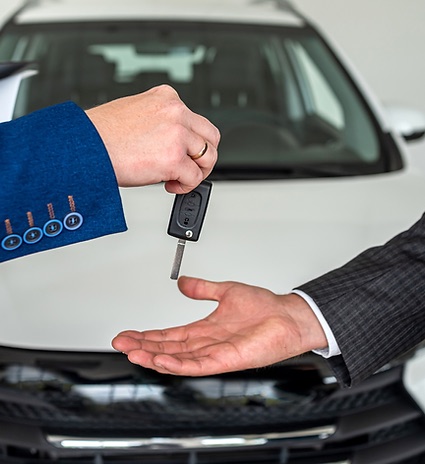 Asesor entregando las llaves de un auto nuevo a un cliente
